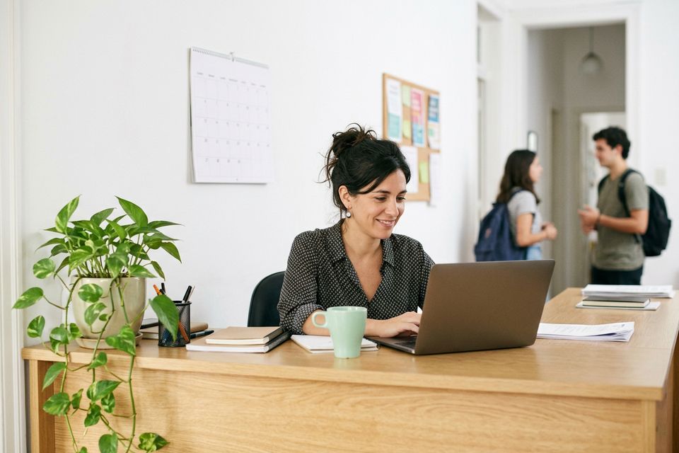 Encargada de un instituto en la recepción, revisando la planilla de cuotas en la notebook